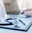 Stethoscope with clipboard and Laptop on desk Doctor working in hospital writing a prescription Healthcare and medical concept test results in background