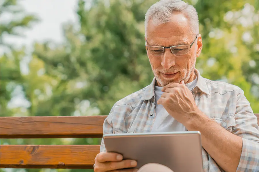 Older man on iPad in park