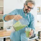 older man making green smoothie