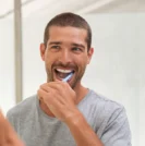 Man brushing teeth in mirror
