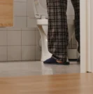 Photo from hallway of man with bph using the bathroom