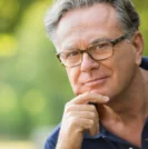 headshot of man with hand on chin looking into the camera