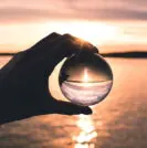 man holding crystal ball on beach