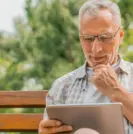 Older man on iPad in park